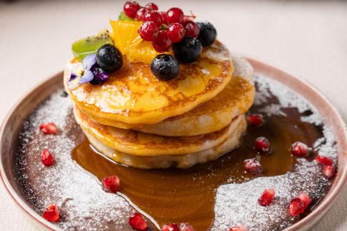 a plate with a stack of pancakes with fruit on it at Barrique Garden in Braşov