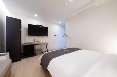 a bedroom with a bed and a television on the wall at Hotel 7 Bricks Gwangju Sangmu in Gwangju
