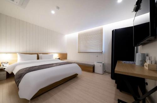 a bedroom with a large white bed and a desk at Hotel 7 Bricks Gwangju Sangmu in Gwangju