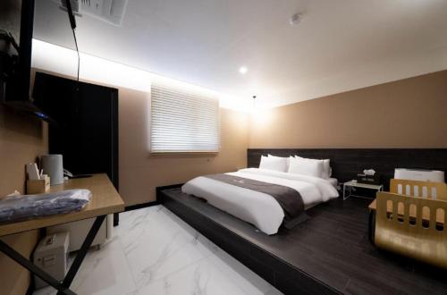 a bedroom with a large white bed and a desk at Hotel 7 Bricks Gwangju Sangmu in Gwangju