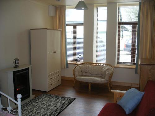 sala de estar con chimenea, silla y ventana en Cooraclare apartment en Cuar an Chláir