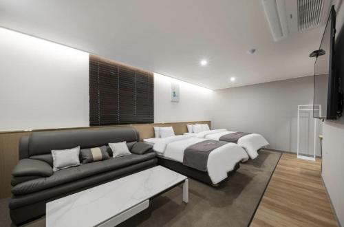 a living room with two beds and a couch at Hotel 7 Bricks Gwangju Sangmu in Gwangju