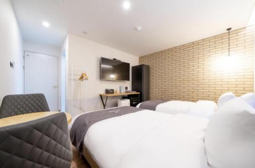 a hotel room with two beds and a tv at Hotel 7 Bricks Gwangju Sangmu in Gwangju