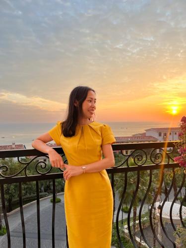 a woman in a yellow dress standing on a balcony at HD Hotel Sunset Town in Phu Quoc