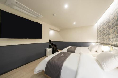 a bedroom with a large bed and a flat screen tv at Hotel 7 Bricks Gwangju Sangmu in Gwangju