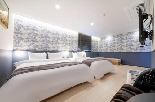 a bedroom with two beds and a painting on the wall at Hotel 7 Bricks Gwangju Sangmu in Gwangju