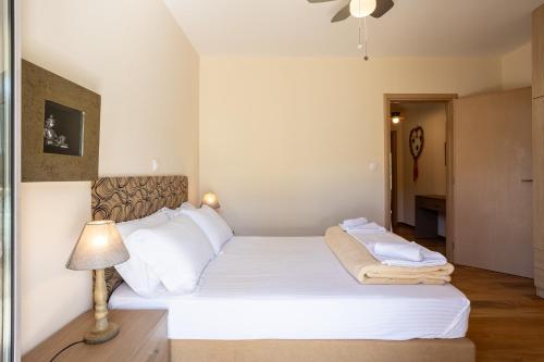 a bedroom with a bed with white sheets and a lamp at Avia Blue Maisonettes - Messinia Gulf Retreat in Avia