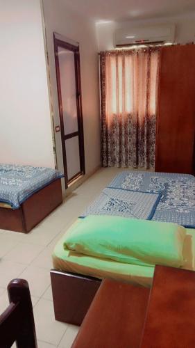 two beds in a room with a table and a window at بيت الشباب بورسعيد in Port Said