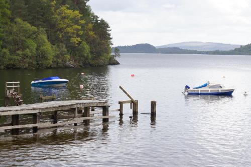two boats are docked at a dock on a lake at Lochlomondlodge22 in Rowardennan