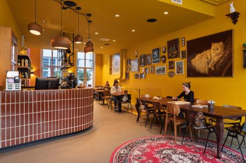 a restaurant with yellow walls and people sitting at tables at Stayokay Hostel Amsterdam Stadsdoelen in Amsterdam