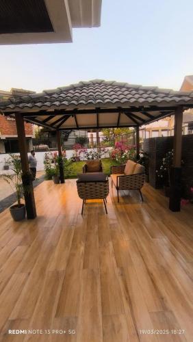 a pavilion with two chairs and a table on a wooden floor at Lions Den luxury 4 BHK with private pool at tiger point near cloud nine in Āmbavna
