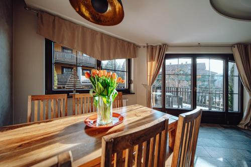 a dining room table with a vase of flowers on it at Norweska Dolina Family&Pet-friendly Resort in Szklarska Poręba