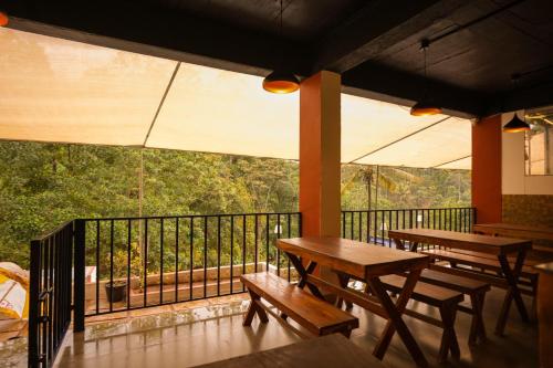 two tables and benches on the balcony of a restaurant at Velvet Vista Munnar in Munnar