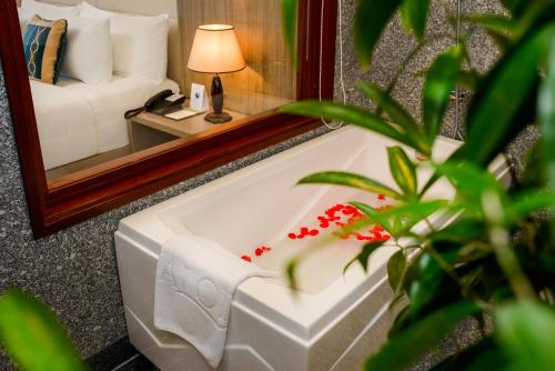 a bathroom with a mirror and a white bath tub at The Nalod Da Nang in Da Nang