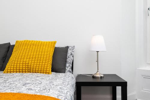 a bed with a yellow pillow and a table with a lamp at 5 Individual Beds - Free Parking in Coatbridge