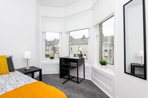 a bedroom with a bed and a desk and windows at 5 Individual Beds - Free Parking in Coatbridge