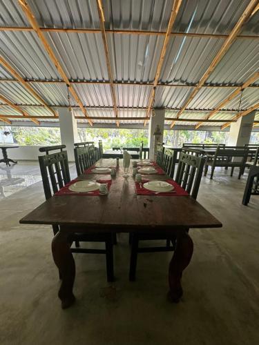 a long wooden table with chairs and plates on it at New Sigiri Kele in Sigiriya
