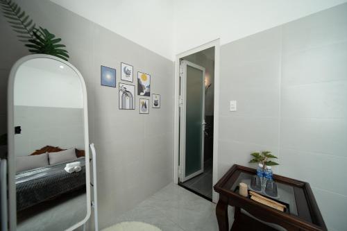 a bathroom with a mirror and a bed and a table at Wings House Homestay Hồ Tràm in Ho Tram
