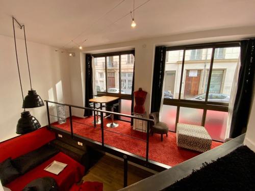 un salon avec un canapé rouge et des fenêtres dans l'établissement LE LOFT des Charmettes, à Lyon