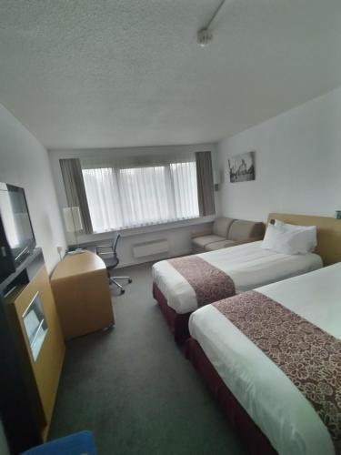 a hotel room with two beds and a flat screen tv at Holiday Inn Lille Ouest Englos by IHG in Englos