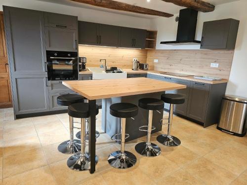 - une cuisine avec une table en bois et des tabourets de bar dans l'établissement Corps de ferme en Aubrac avec jacuzzi, à Montpeyroux