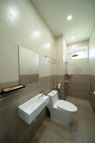 a bathroom with a toilet and a sink and a mirror at Wings House Homestay Hồ Tràm in Ho Tram