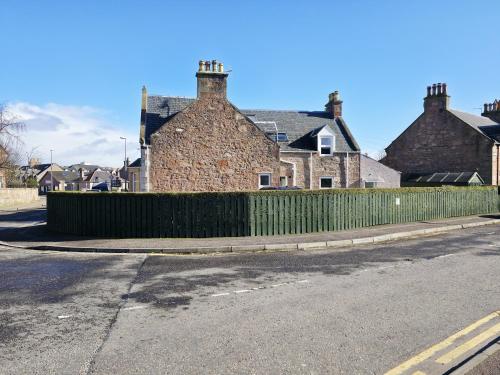 a green fence in front of a brick building at Inverness City 4 Bedroom house free parking in Inverness