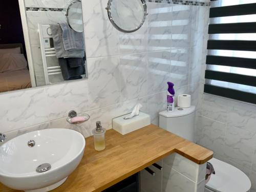 un bagno bianco con lavandino e specchio di Chambres tout confort du Tilleul a Bosc-Bénard-Commin