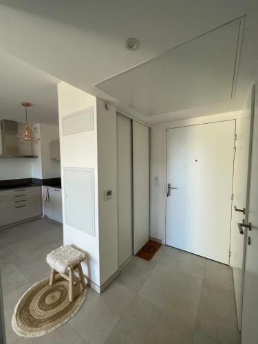une pièce blanche avec un tabouret et une porte dans l'établissement Appartement 2P Cros de Cagnes à 2 pas de la mer, à Cagnes-sur-Mer