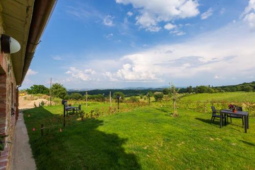 a yard with two chairs and a table in a field at Agriturismo Palazzo Bandino - Wine cellar, on reservation restaurant and spa in Chianciano Terme