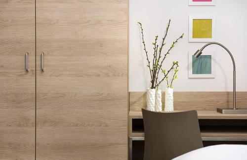 a kitchen with wooden cabinets and a desk with a chair at Business & Budget Hotel Tessin in Munich