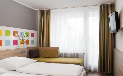 ein Hotelzimmer mit einem Bett und einem Fenster in der Unterkunft Business & Budget Hotel Tessin in München