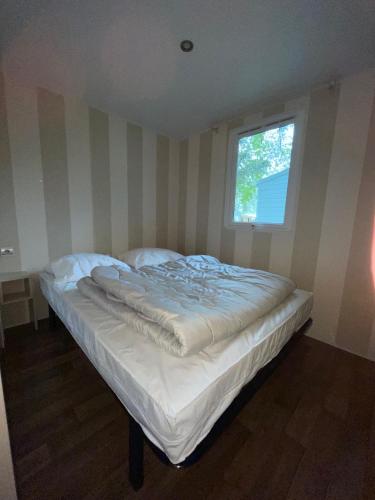 un lit blanc dans une chambre avec une fenêtre dans l'établissement Chez Philippe et Sylvie - 2 bungalows pour 5 proche Europa-Park, à Boofzheim