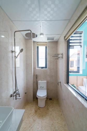 a bathroom with a toilet and a sink and a window at Peaceful House Hostel in Dong Hoi