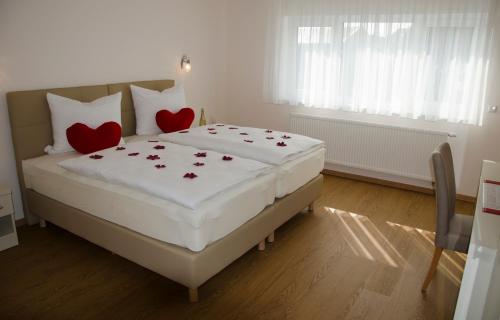 Schlafzimmer mit einem Bett mit roten Herzen in der Unterkunft Kraichgauhotel in Kraichtal