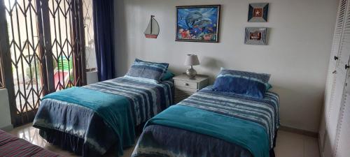 a bedroom with two beds and a window at On The Beach @ South Sands.No 2 in Port Edward