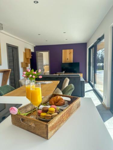 a wooden tray of food on a table with a glass of orange juice at Domaine de Haslach, The Originals Collection, Résidence de Tourisme in Munster