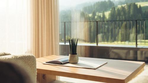 a table with a vase on it with a window at Brunelle Seiser Alm Lodge in Alpe di Siusi