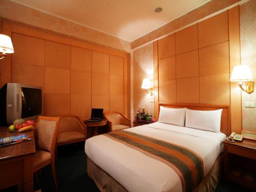 a hotel room with a bed and a desk and a tv at Da Shih Hotel in Hualien City