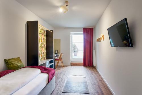 a hotel room with a bed and a flat screen tv at Zur Krone in Neuötting