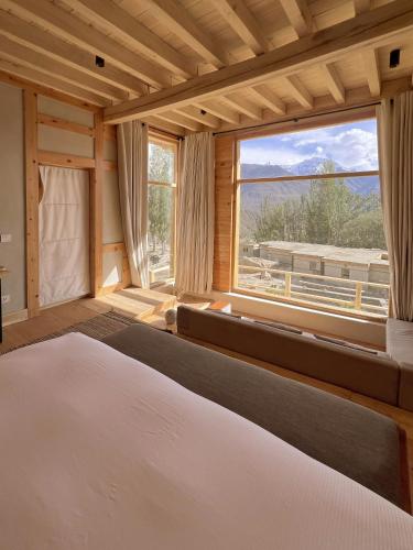 a bedroom with a bed and a large window at The Rihla Hunza - Managed By Luxus in Hunza