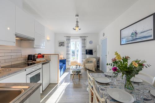 - une cuisine et un salon avec une table fleurie dans l'établissement Résidence du Port, à La Trinité-sur-Mer