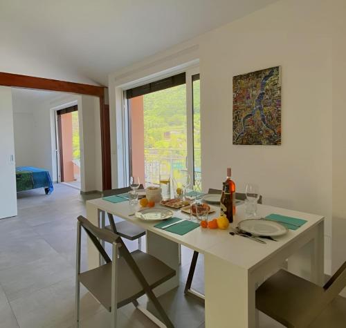 Un comedor blanco con una mesa y sillas blancas. en La Rondinella ComoLake, en Argegno