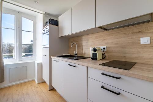 une cuisine avec des armoires blanches, un évier et une fenêtre dans l'établissement Sept îles - studio - centre-ville - TV, à Vannes