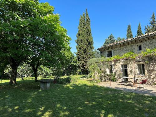 an old stone building with trees and a yard at Le Manou Maison de charme en Drôme provençale in Marsanne