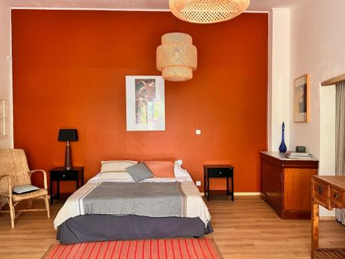a bedroom with a bed with an orange wall at Le Manou Maison de charme en Drôme provençale in Marsanne