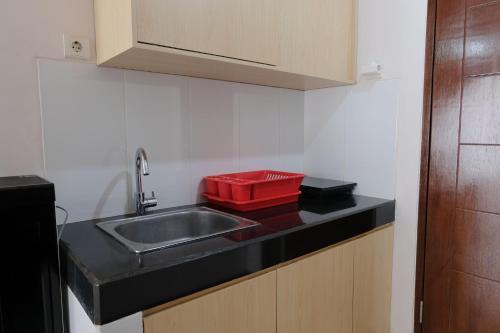 eine Küche mit einem Waschbecken und einem roten Tablett auf der Theke in der Unterkunft Cozy and Strategic 2BR Apartment at Gateway Pasteur By Travelio in Bandung