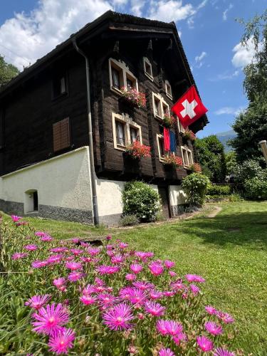 ein Haus mit einer Flagge und Blumen im Hof in der Unterkunft Chalet Piumogna in Faido