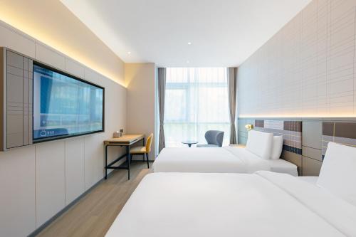 a hotel room with two beds and a flat screen tv at HomeInn Plus at China Intl Exhibition Center and Liufang Subway Stn in Beijing
