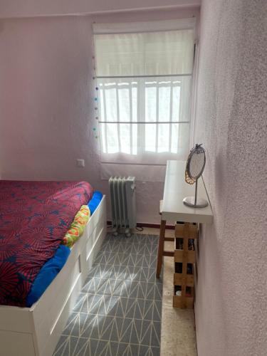 a bedroom with a bed and a desk and a window at Coqueta habitación doble in Mairena del Aljarafe